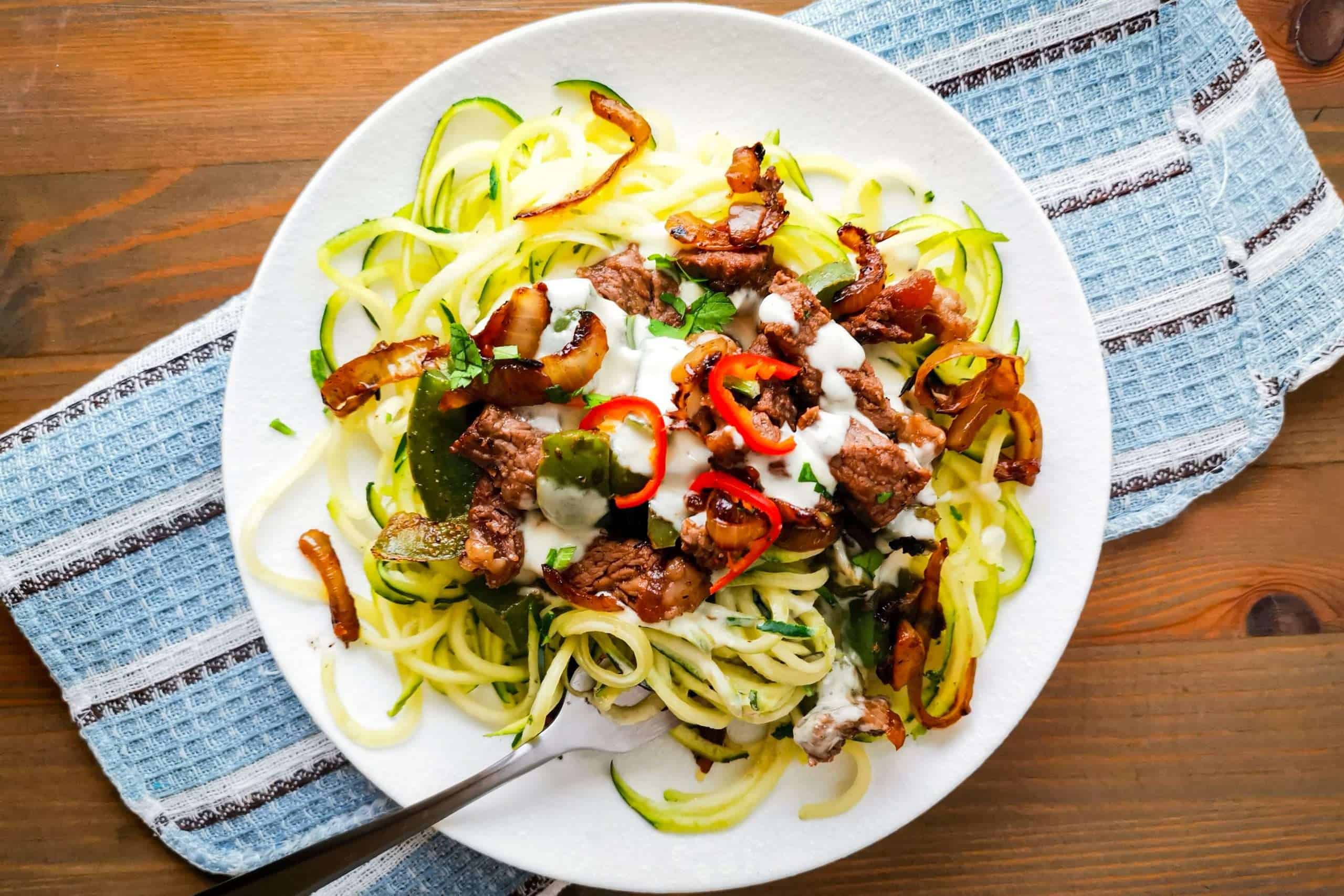 Low Carb Philly Cheesesteak Zoodles topped with onions and hot peppers