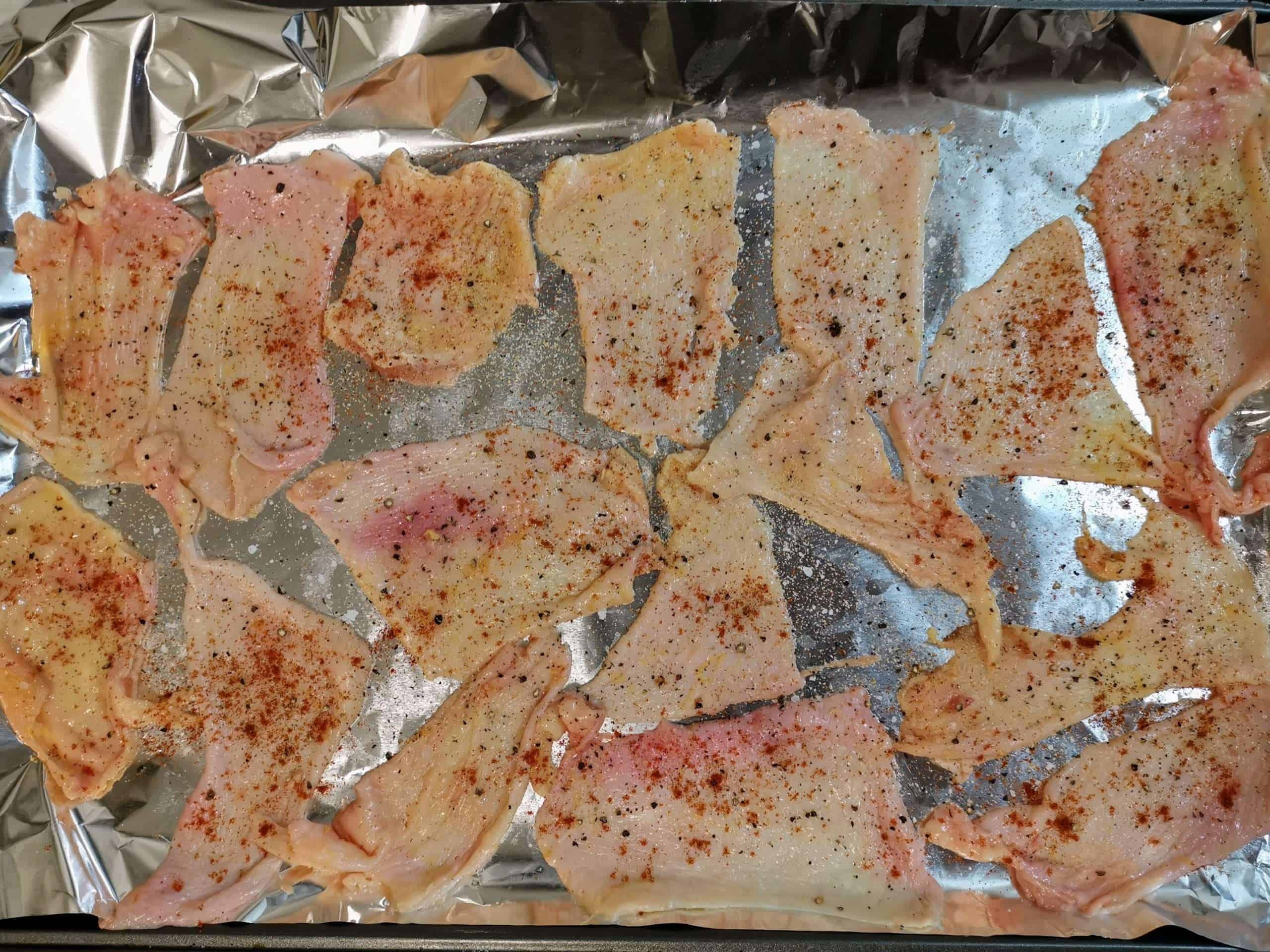 Raw chicken skins ready to be turned into chips on a a baking sheet