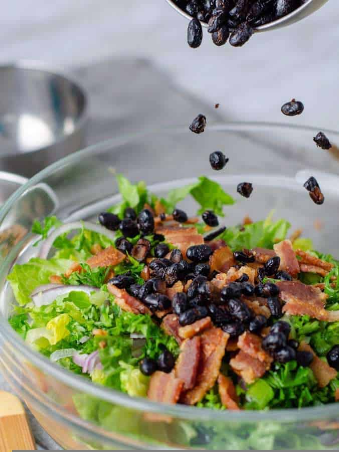 Keto fried black beans sprinkled on a a caesar salad
