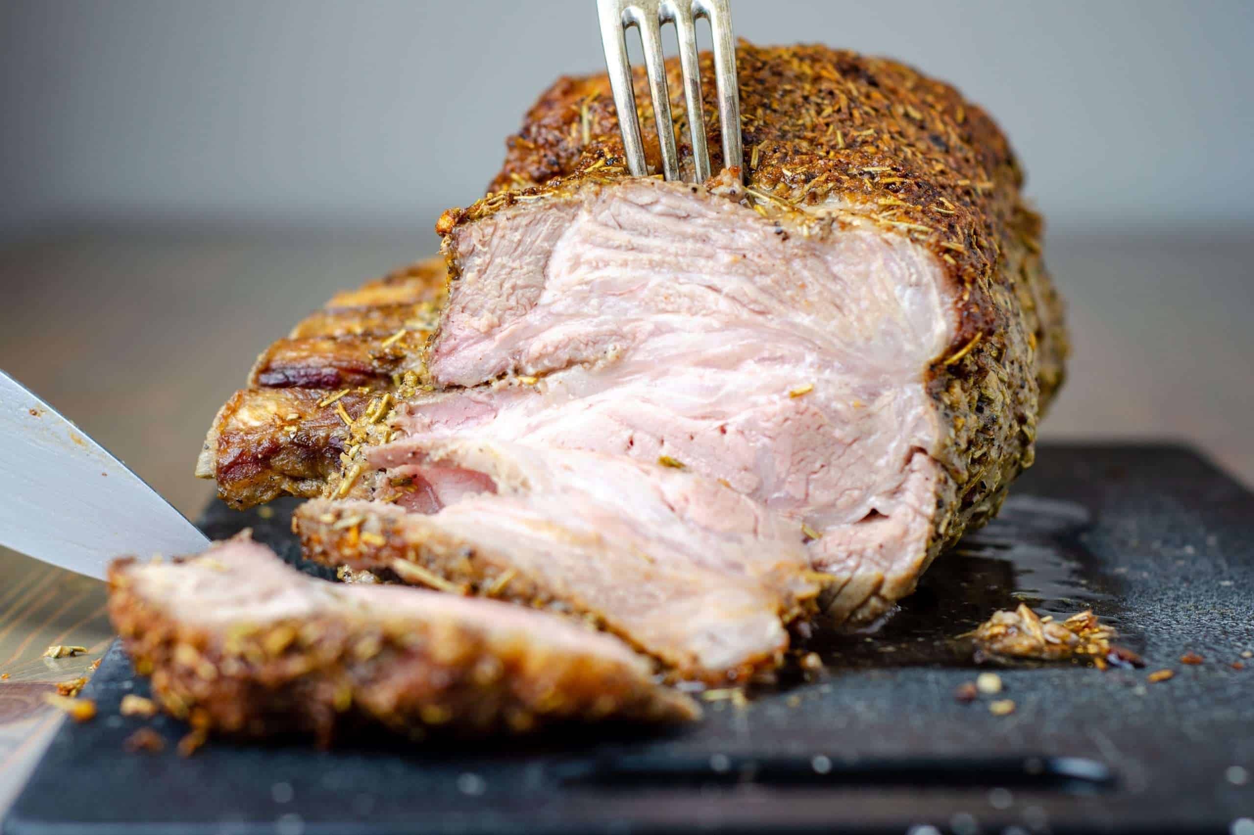 Herb Crusted keto pork roast being sliced on a cutting board