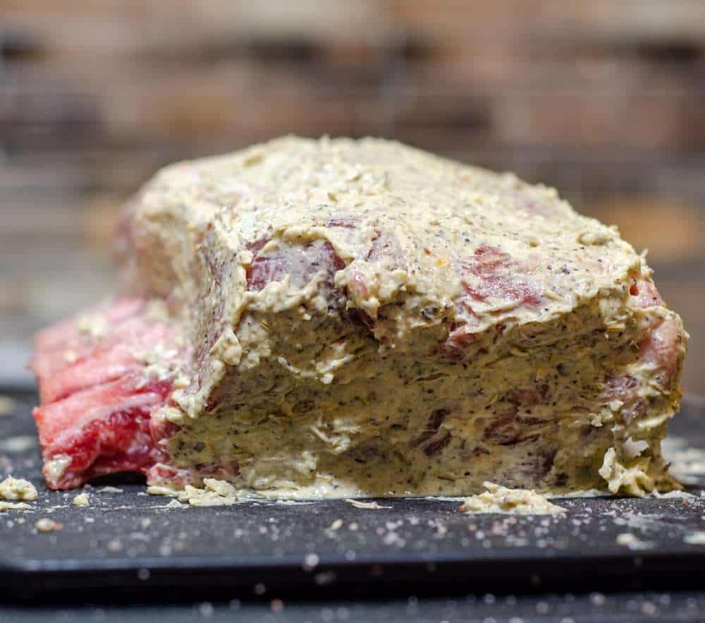Pork ribeye roast raw, slathered in a herb filled butter