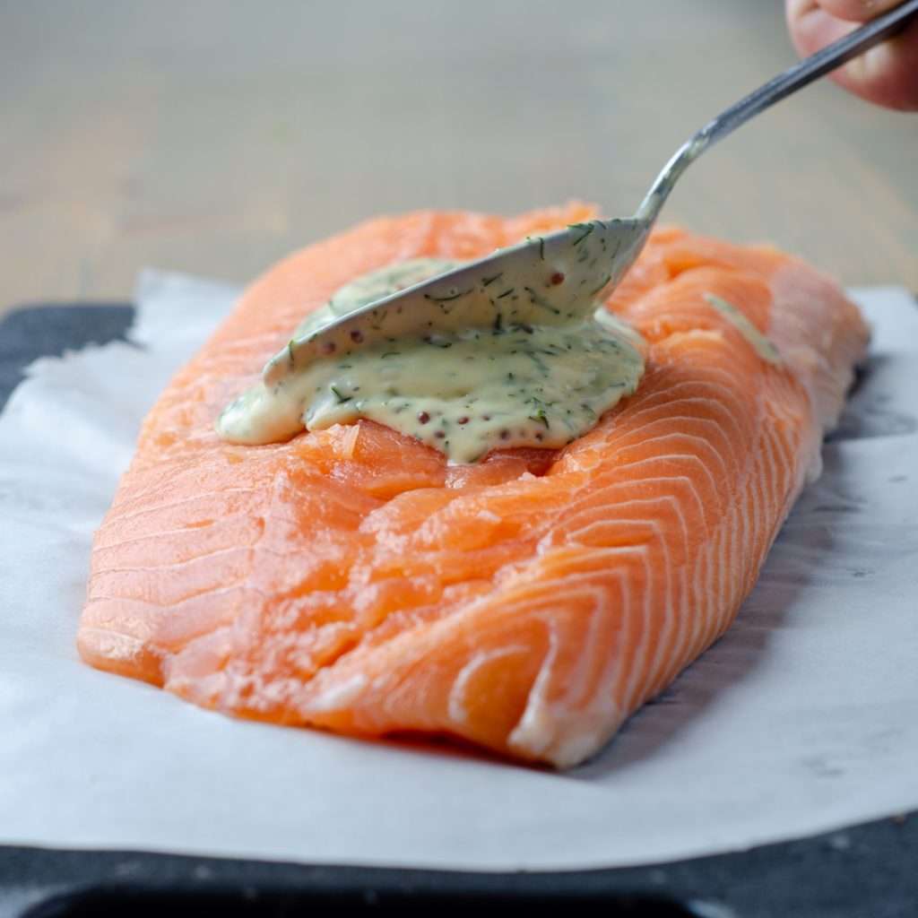 Raw salmon with honey dijon mayo being spread over top