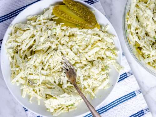 Dill pickle keto coleslaw in a bowl garnished with a pickle