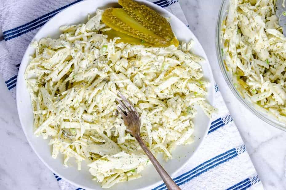 Dill pickle keto coleslaw in a bowl garnished with a pickle