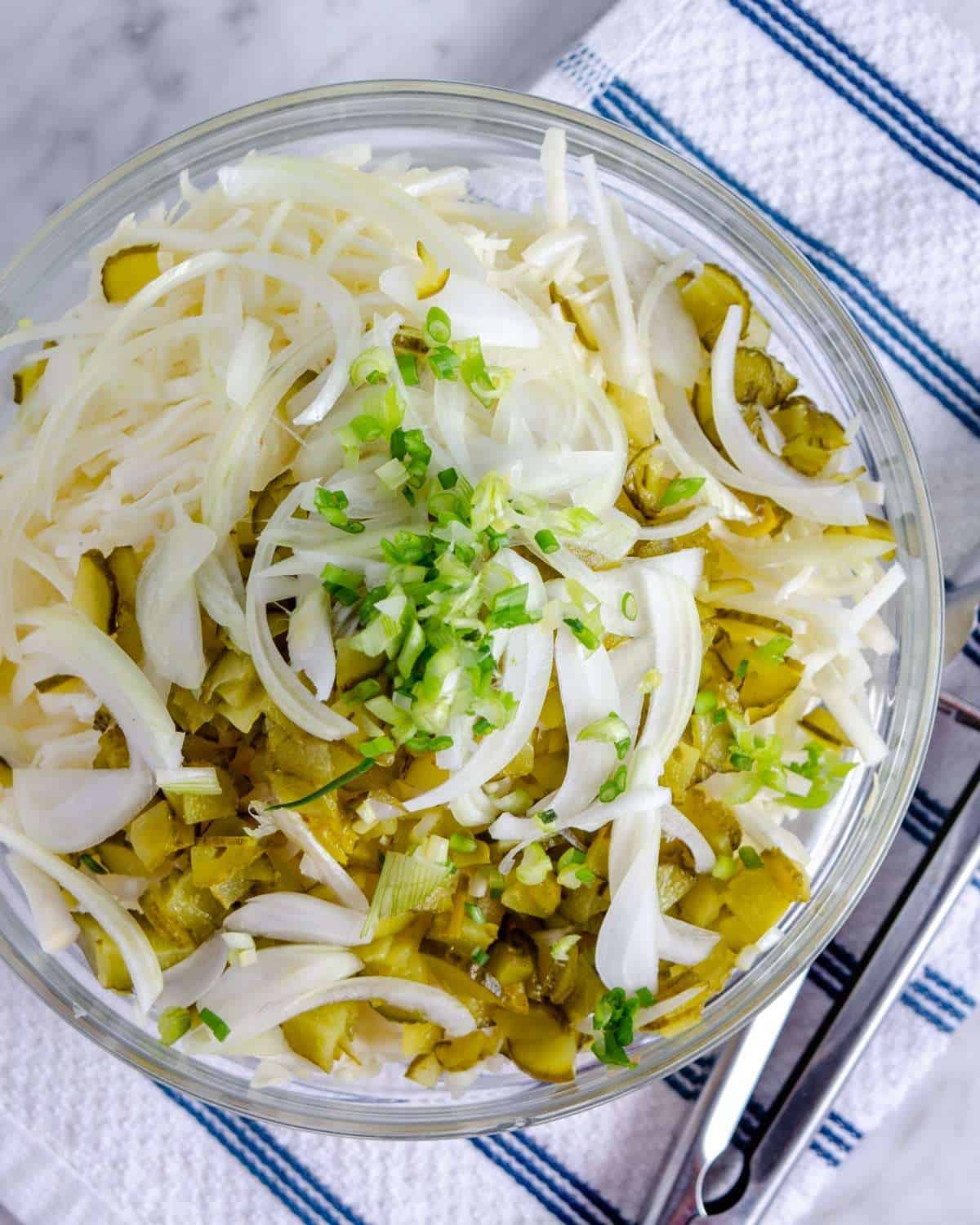 Low carb coleslaw with dill pickles, and onions in a bowl
