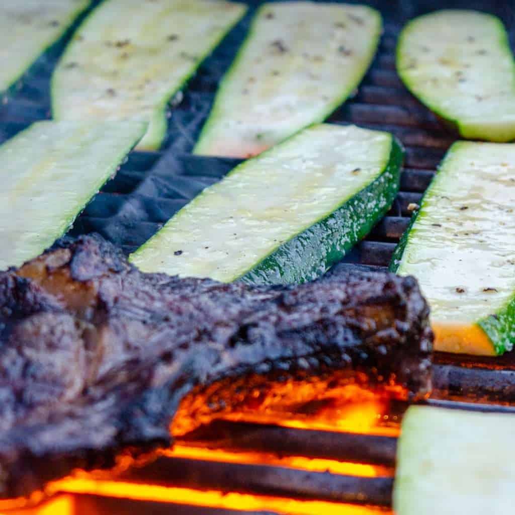 Slabs of zucchini on a grill with steak