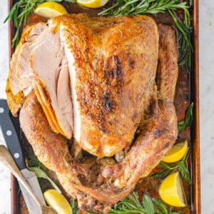 Sliced dry brine turkey on a tray garnished with lemons and losemary