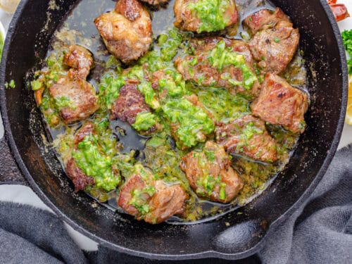 Pan seared steak bites in a cast iron with butter and homemade chimichurri
