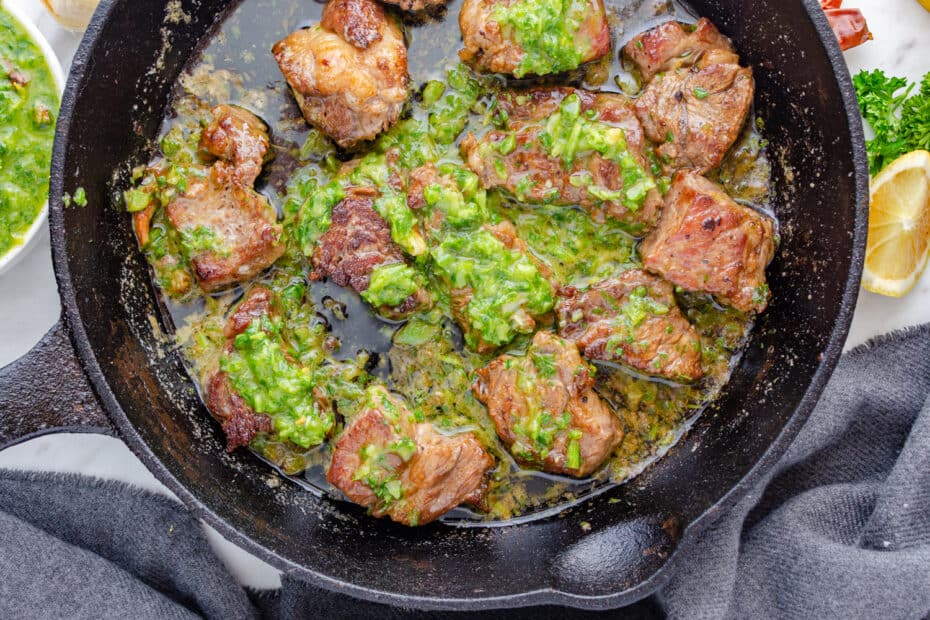 Pan seared steak bites in a cast iron with butter and homemade chimichurri