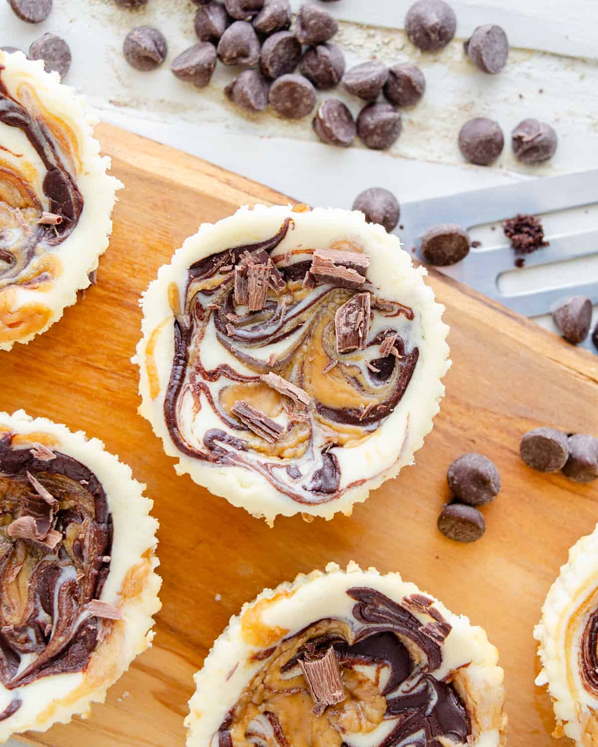 Chocolate peanut butter muffin tin keto cheesecakes on a wooden board.