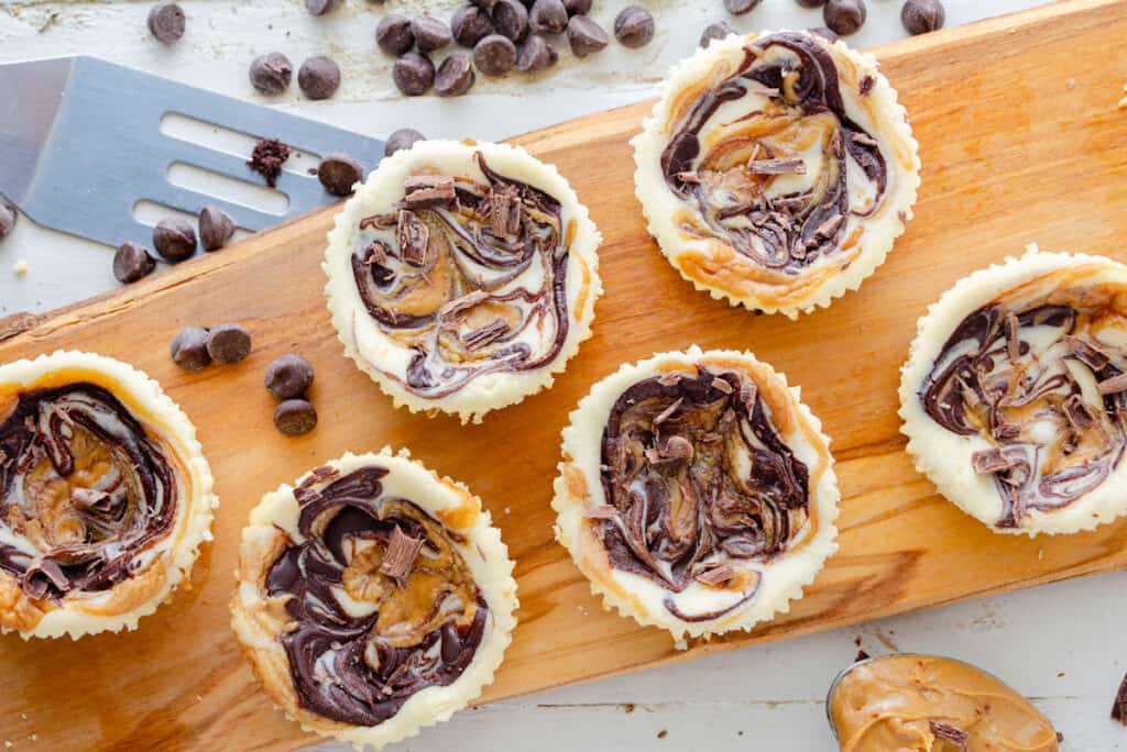 Chocolate Peanut Butter Mini Keto cheesecakes on a wooden board