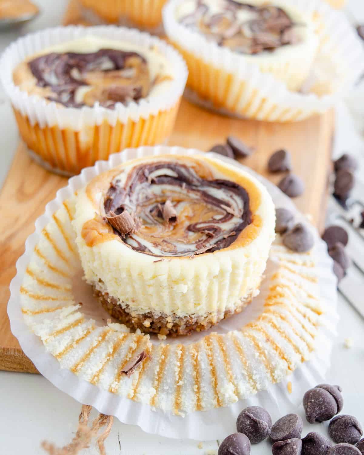 Muffin tin chocolate peanut butter keto cheesecakes being unwrapped from muffin papers.
