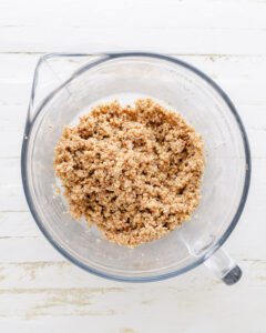 Crumbly pecan cheesecake crust mixture in a bowl.