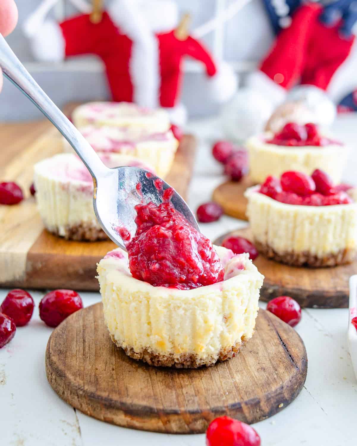 Cran raspberry compote being spooned onto a mini keto cheesecake.