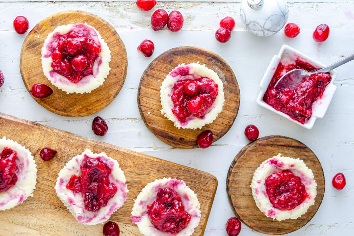 Mini cran raspberry keto cheesecakes on wooden plates.