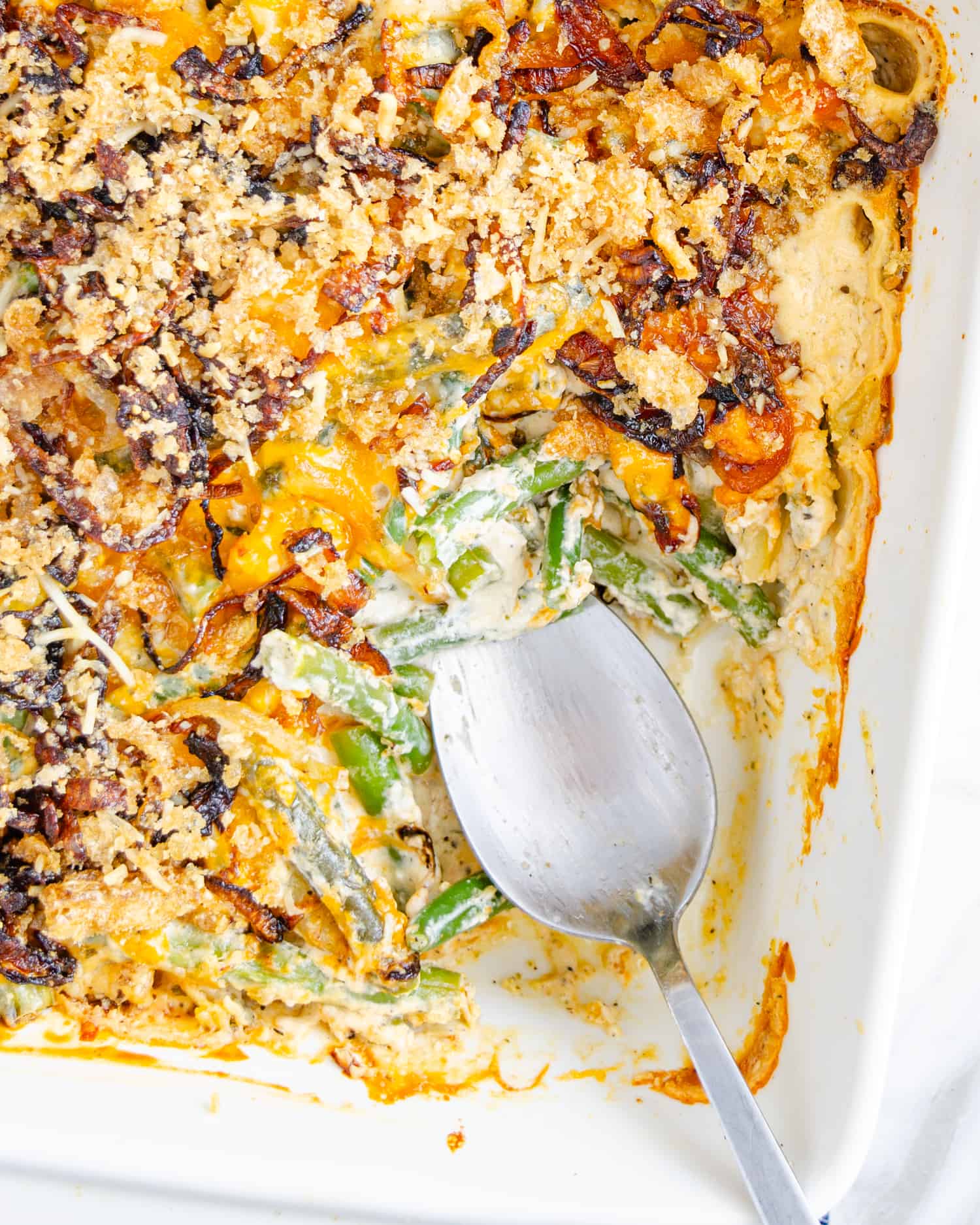 keto green bean casserole with a scoop out showing the creamy green bean layer.