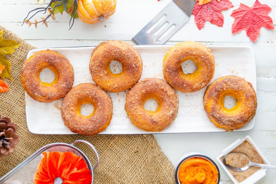 Almond Flour Pumpkin spice donuts on a tray with autumn decorations around.