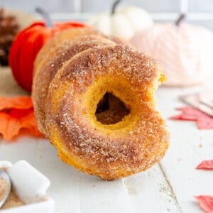 Keto pumpkin Spice donut stacked on a white surface with fall decorations in the background.
