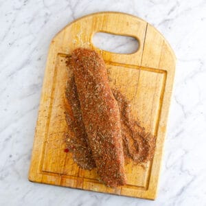 Spice rubbed pork tenderloin on a cutting board.