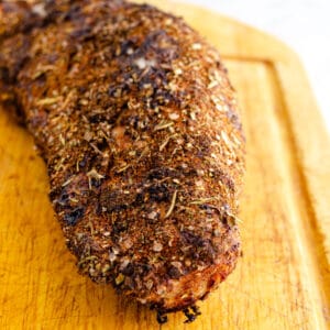 Air fried, spice rubbed pork tenderloin unsliced on a cutting board.