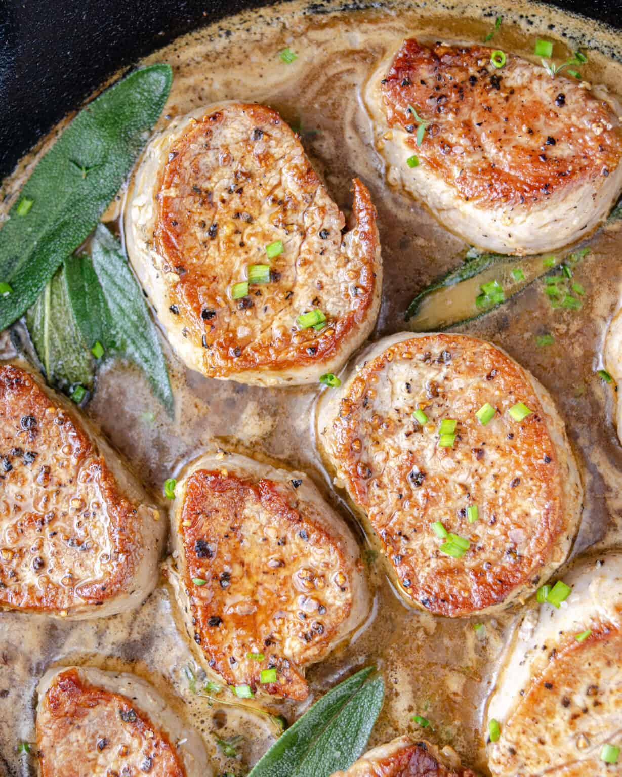 Seared pork medallions with brown butter gravy in a cast iron skillet.