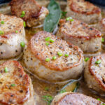 Golden brown pan seared pork medallions in a cast iron skillet.