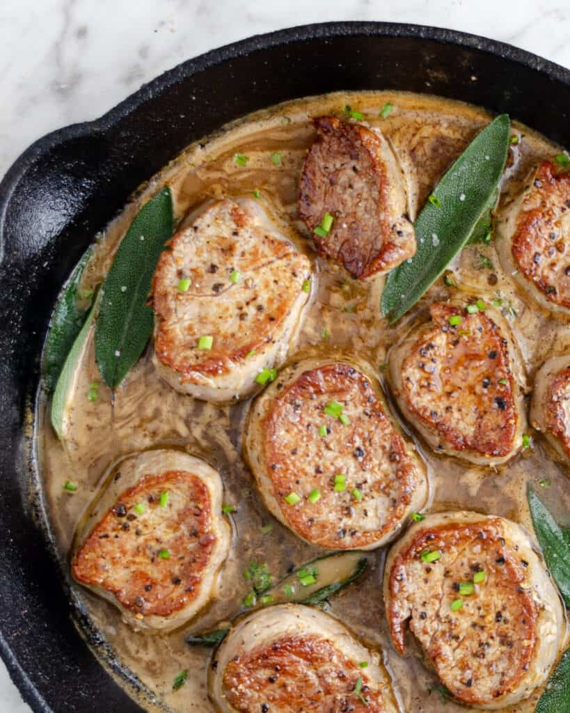 Perfectly seared cast iron pork medallions in gravy.